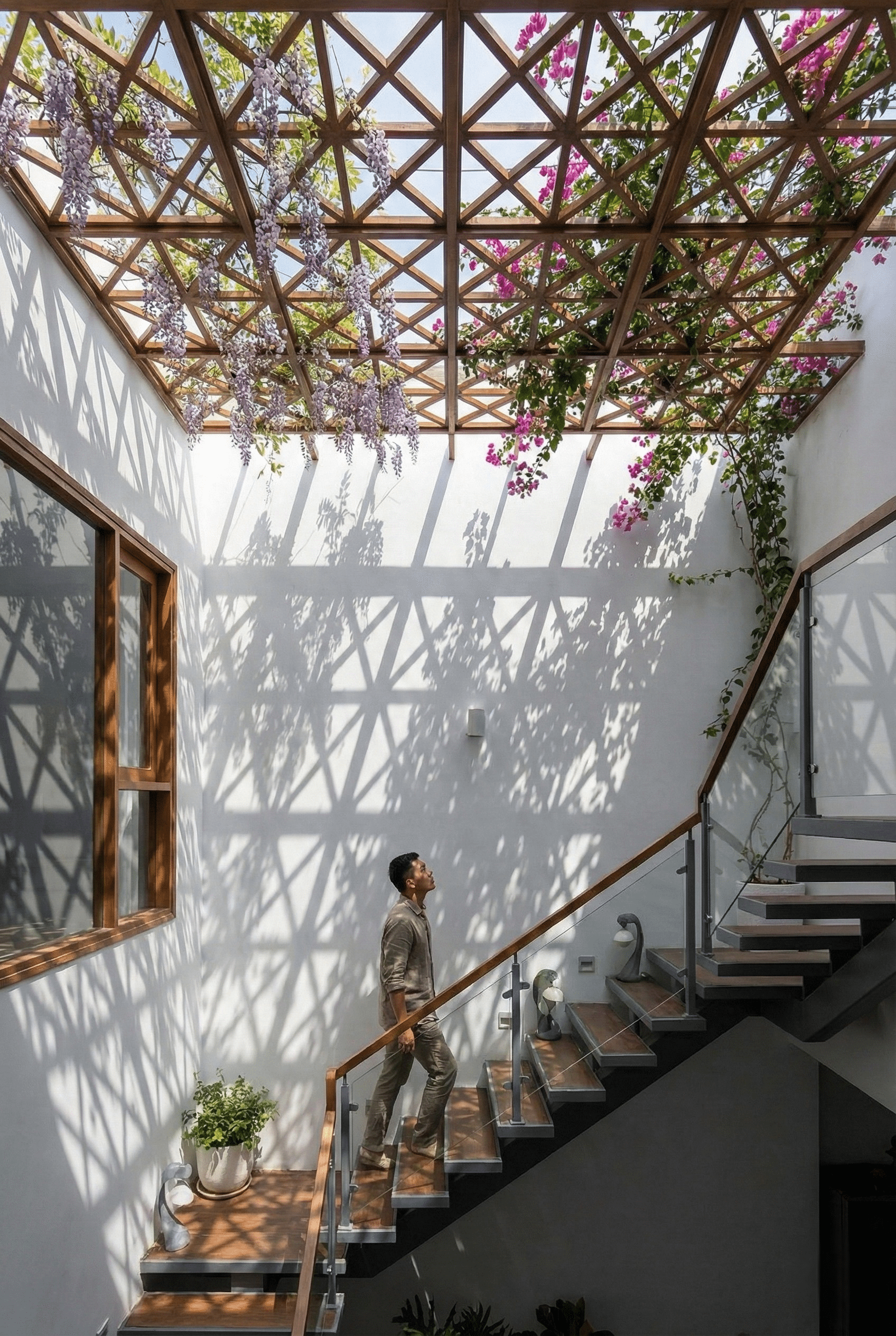 Giếng trời mái kính năng lượng mặt trời được rải đá tự nhiên bên trên giúp giảm 40-45% nhiệt lượng. Ánh sáng xuyên qua lớp đá tạo hiệu ứng bóng đổ loang lổ như nắng xuyên qua kẽ lá in trên tường trắng, mang lại ánh sáng tự nhiên dịu mát cho nhà phố.